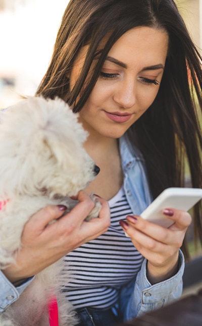Lady with puppy using smartphone Lady with puppy using smartphone: Download our App in Waynesboro